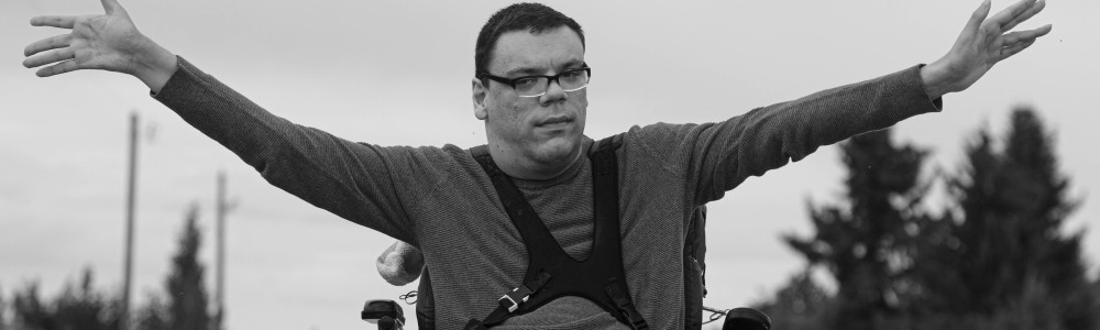 Person im Rollstuhl streckt seine Arme zur Seite